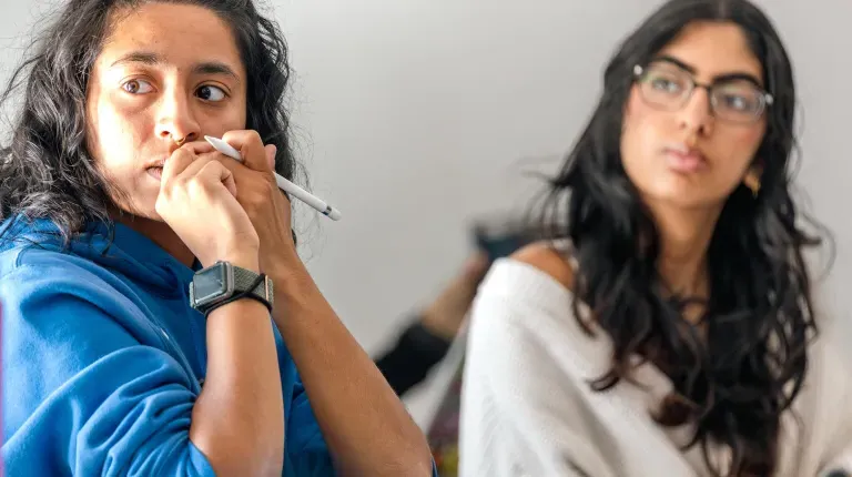 Two students listen to classroom conversation