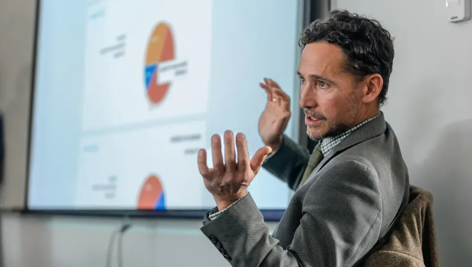 A UNE professor leads discussion in front of a presentation